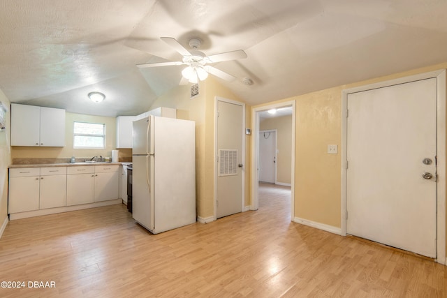 kitchen with white fridge, white cabinetry, light wood-type flooring, vaulted ceiling, and ceiling fan