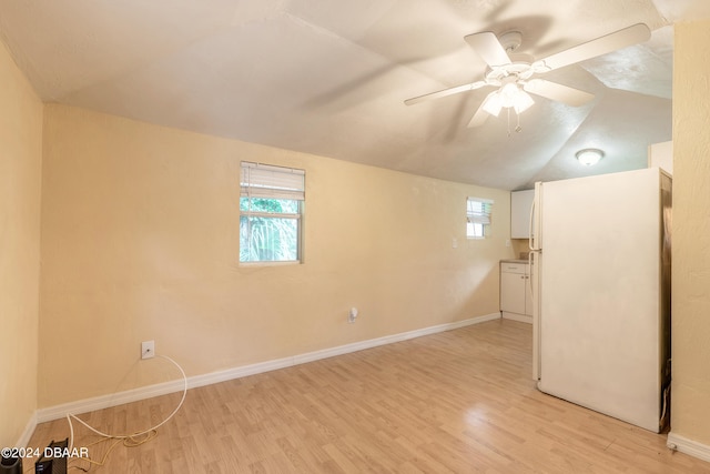 basement featuring light wood-type flooring, ceiling fan, and white refrigerator