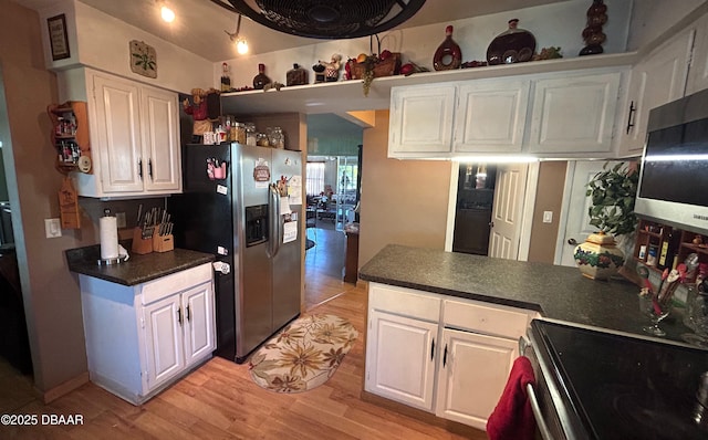 kitchen with kitchen peninsula, appliances with stainless steel finishes, white cabinetry, and light hardwood / wood-style flooring