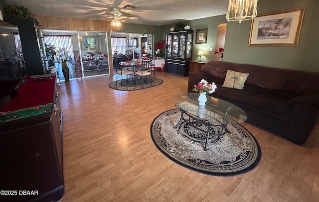 living room with hardwood / wood-style flooring and ceiling fan with notable chandelier