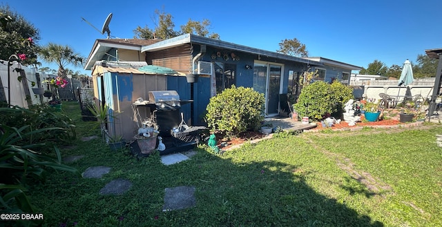 back of house featuring a lawn and an outdoor structure