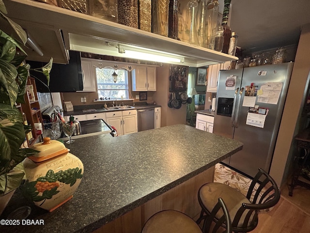 kitchen with sink, appliances with stainless steel finishes, kitchen peninsula, and a breakfast bar