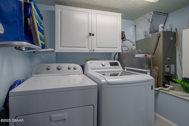 laundry area with cabinets, washer and clothes dryer, water heater, and a textured ceiling