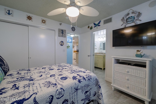 bedroom with sink, ceiling fan, ensuite bathroom, a textured ceiling, and a closet