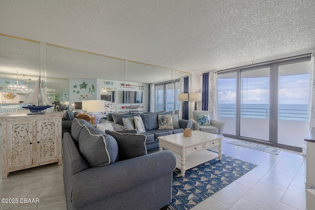 tiled living room with a water view, a wall of windows, and a textured ceiling