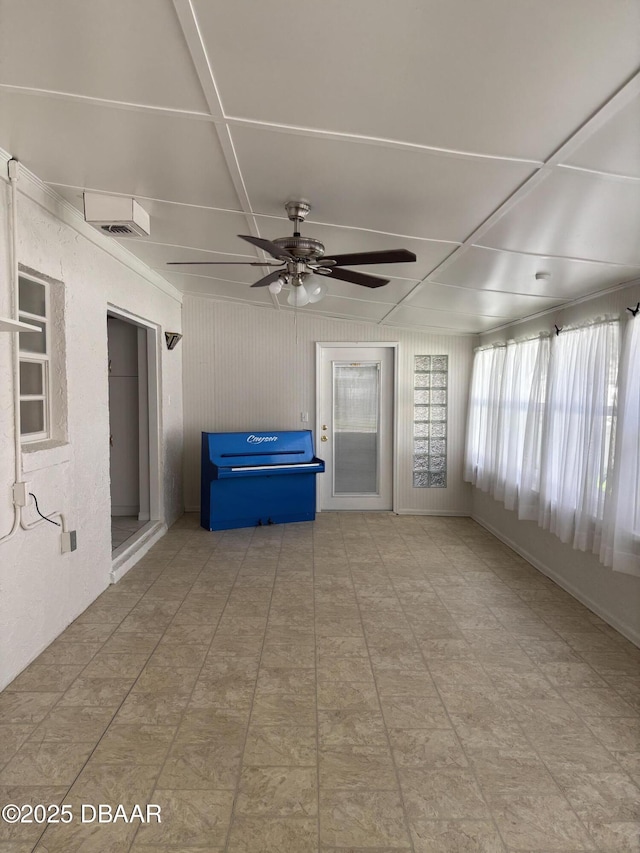 unfurnished sunroom featuring ceiling fan