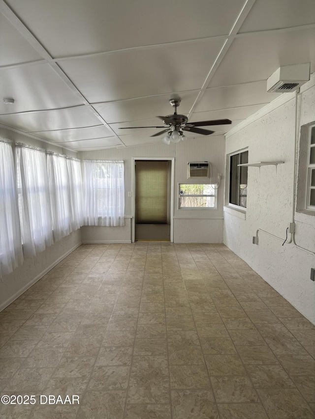 unfurnished sunroom with a wall unit AC and ceiling fan