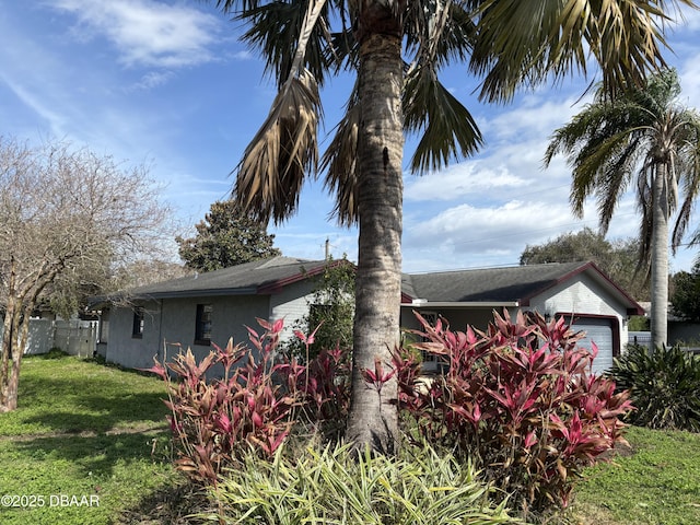 view of side of home featuring a garage and a lawn