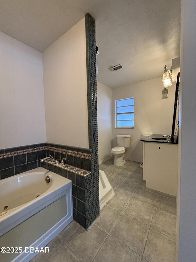 bathroom featuring a bathing tub, vanity, tile patterned floors, and toilet