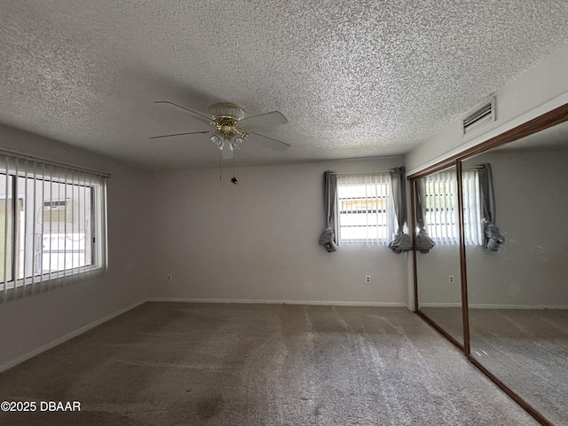 unfurnished bedroom with a textured ceiling, carpet floors, a closet, and ceiling fan