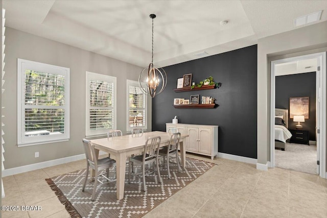 dining room with light tile patterned floors, a tray ceiling, and a notable chandelier