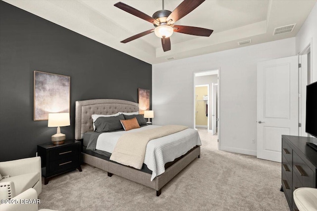 carpeted bedroom featuring a raised ceiling, connected bathroom, and ceiling fan