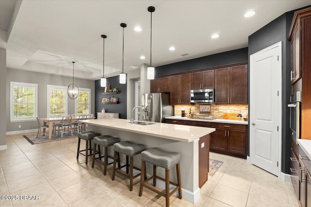 kitchen with a kitchen island with sink, dark brown cabinets, stainless steel appliances, and sink