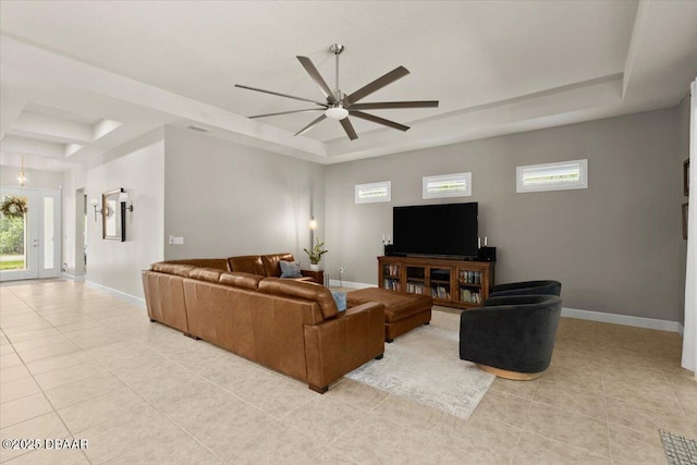 living room featuring a tray ceiling, plenty of natural light, and light tile patterned flooring