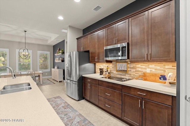 kitchen with an inviting chandelier, hanging light fixtures, sink, decorative backsplash, and appliances with stainless steel finishes