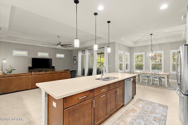 kitchen with pendant lighting, a center island with sink, ceiling fan with notable chandelier, sink, and appliances with stainless steel finishes