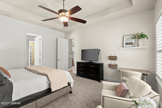 bedroom with ceiling fan, a raised ceiling, and light colored carpet