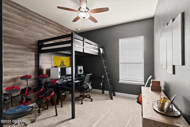 carpeted bedroom featuring wooden walls and ceiling fan