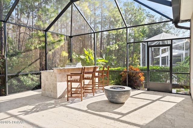 view of patio with exterior bar, an outdoor kitchen, and a lanai