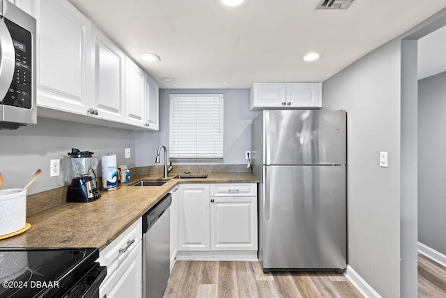 kitchen featuring white cabinetry, sink, light wood-type flooring, and appliances with stainless steel finishes