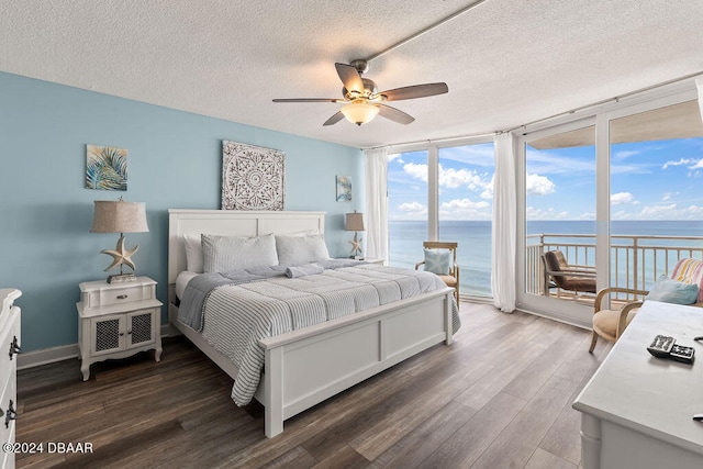 bedroom featuring a water view, dark wood-type flooring, access to exterior, a textured ceiling, and ceiling fan