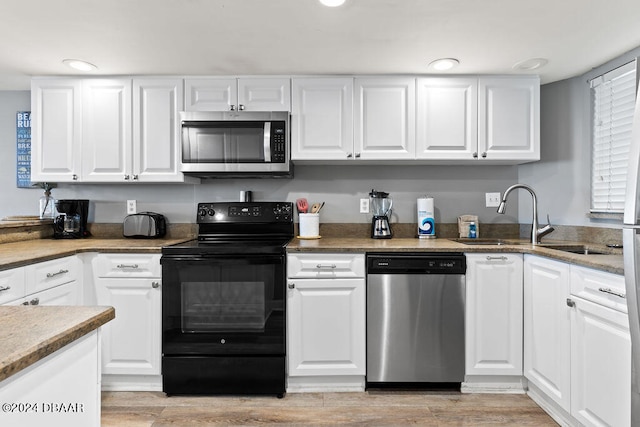 kitchen featuring white cabinetry, light wood-type flooring, stainless steel appliances, and sink