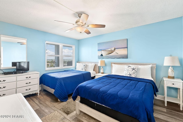 bedroom featuring dark hardwood / wood-style flooring, a textured ceiling, and ceiling fan