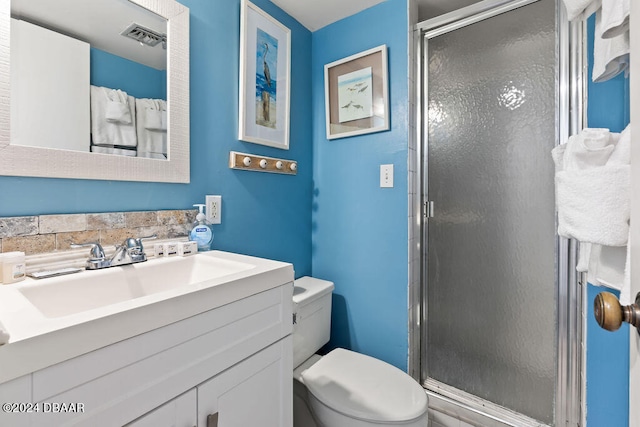 bathroom featuring vanity, toilet, and a shower with shower door