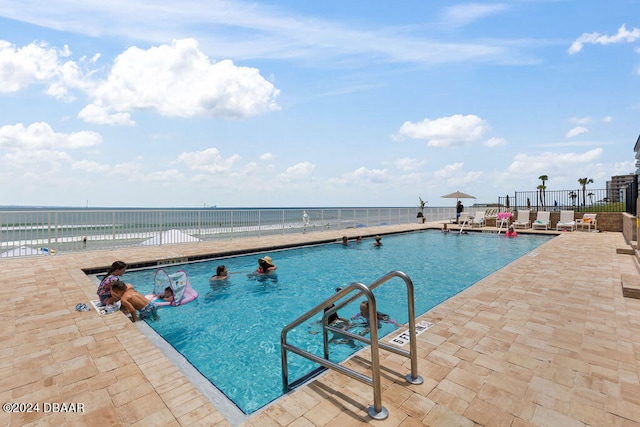 view of swimming pool featuring a patio and a water view