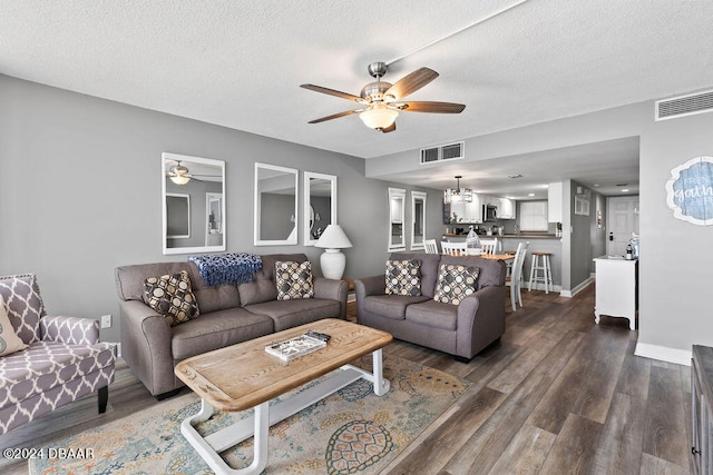 living room featuring ceiling fan, a textured ceiling, and dark hardwood / wood-style flooring