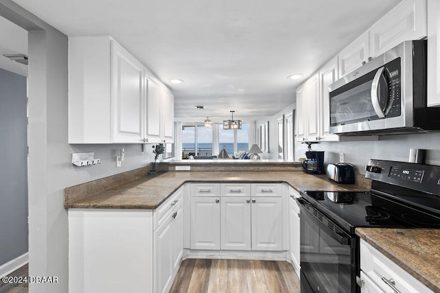 kitchen featuring kitchen peninsula, an inviting chandelier, light hardwood / wood-style flooring, white cabinets, and electric range