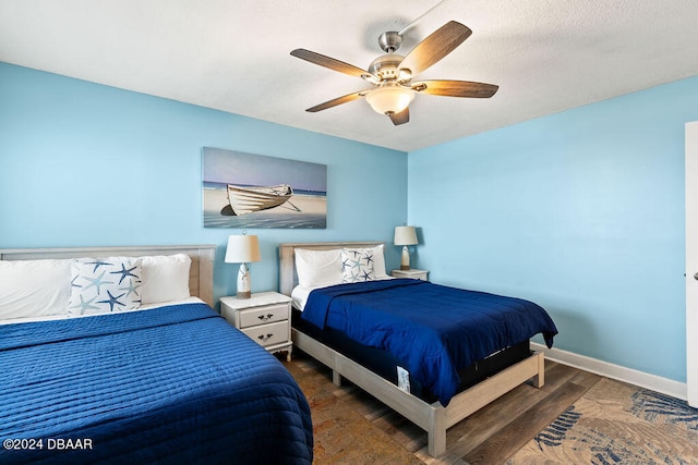 bedroom with a textured ceiling, dark hardwood / wood-style flooring, and ceiling fan