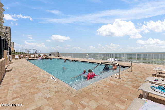 view of swimming pool featuring a patio and a water view