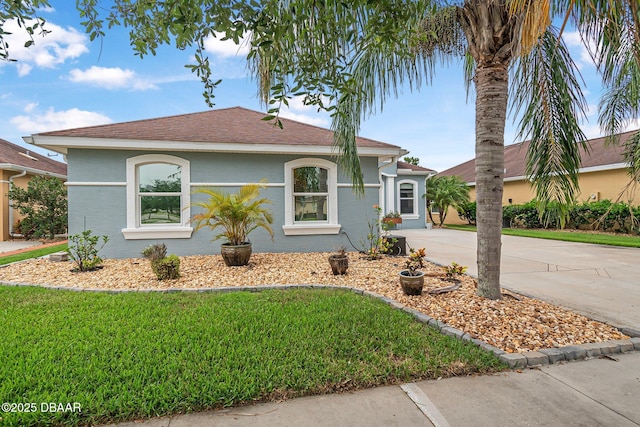 3345 Tesoro Cir, New Smyrna Beach, FL 32168 - view of front of house with driveway, a front yard, roof with shingles, and stucco siding