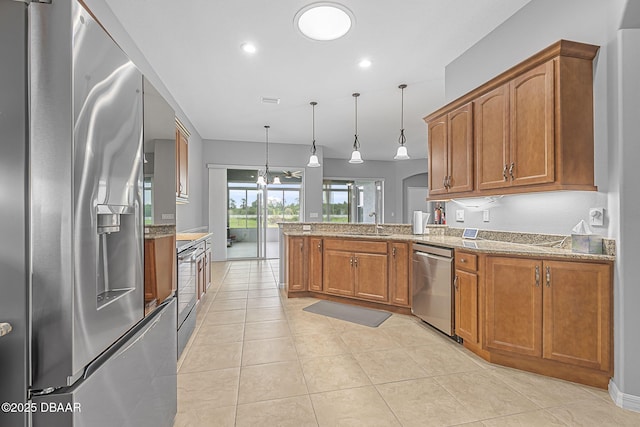 3345 Tesoro Cir, New Smyrna Beach, FL 32168 - kitchen featuring appliances with stainless steel finishes, a peninsula, brown cabinets, a sink, and decorative light fixtures