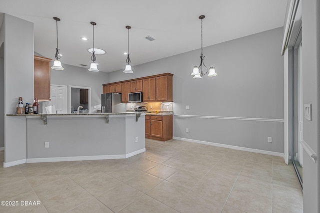 3345 Tesoro Cir, New Smyrna Beach, FL 32168 - kitchen with appliances with stainless steel finishes, a sink, a breakfast bar area, light stone countertops, and a peninsula