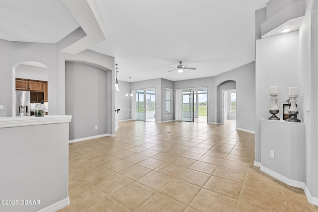 3345 Tesoro Cir, New Smyrna Beach, FL 32168 - unfurnished living room with a ceiling fan, light tile patterned flooring, arched walkways, and baseboards