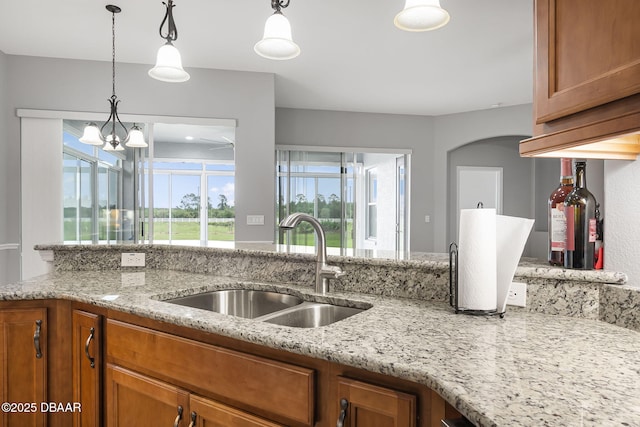3345 Tesoro Cir, New Smyrna Beach, FL 32168 - kitchen featuring a sink, brown cabinets, light stone countertops, and decorative light fixtures