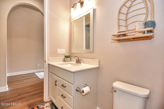 bathroom with toilet, vanity, and hardwood / wood-style flooring