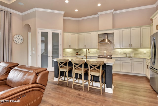 kitchen with light hardwood / wood-style floors, light stone countertops, wall chimney range hood, and stainless steel appliances