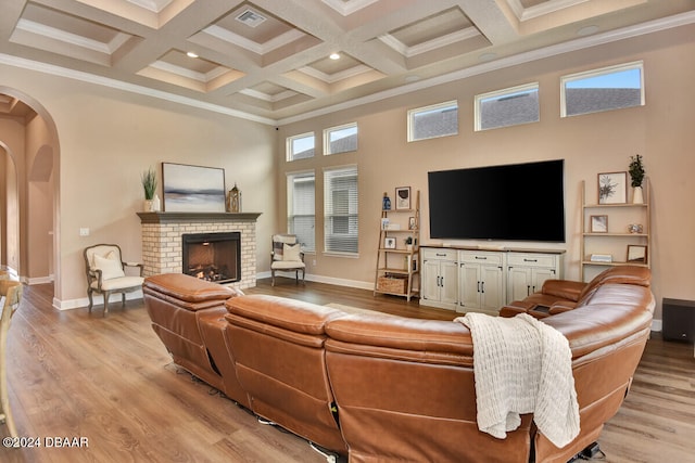 living room with crown molding, light hardwood / wood-style flooring, plenty of natural light, and a brick fireplace