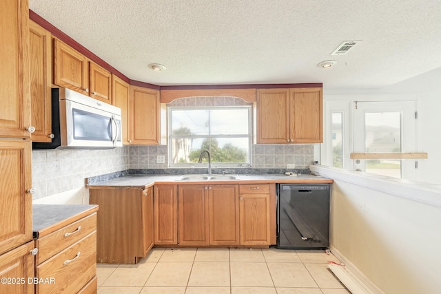 kitchen with black dishwasher, stainless steel microwave, brown cabinetry, light tile patterned flooring, and a sink