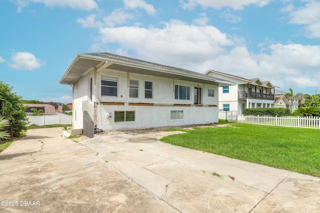 back of house featuring fence, a lawn, and stucco siding