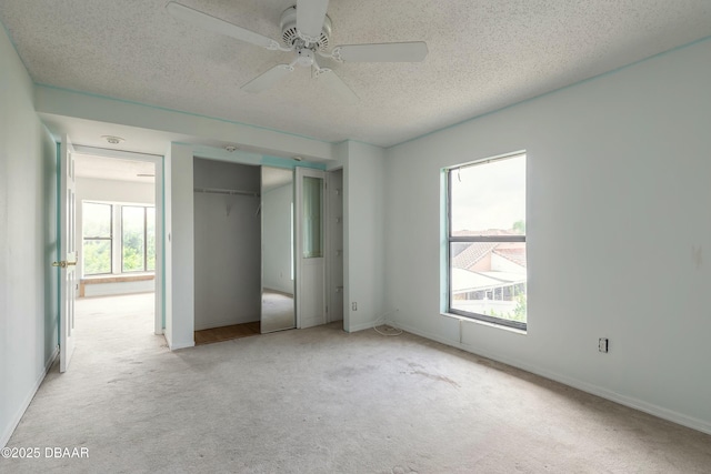 unfurnished bedroom featuring light colored carpet, a textured ceiling, and multiple windows