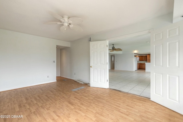 empty room with light wood finished floors, visible vents, and a ceiling fan