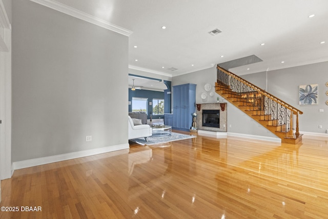4210 S Peninsula Dr, Port Orange, FL 32127 - unfurnished living room featuring a glass covered fireplace, ornamental molding, stairway, wood finished floors, and a ceiling fan