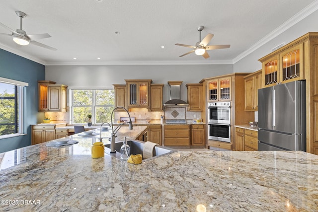 4210 S Peninsula Dr, Port Orange, FL 32127 - kitchen featuring stainless steel appliances, wall chimney exhaust hood, ceiling fan, brown cabinets, and crown molding