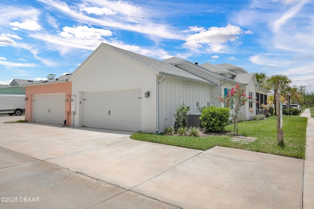 623 Margaritaville Ave, Daytona Beach, FL 32124 - view of side of property with an attached garage, concrete driveway, board and batten siding, a shingled roof, and a yard