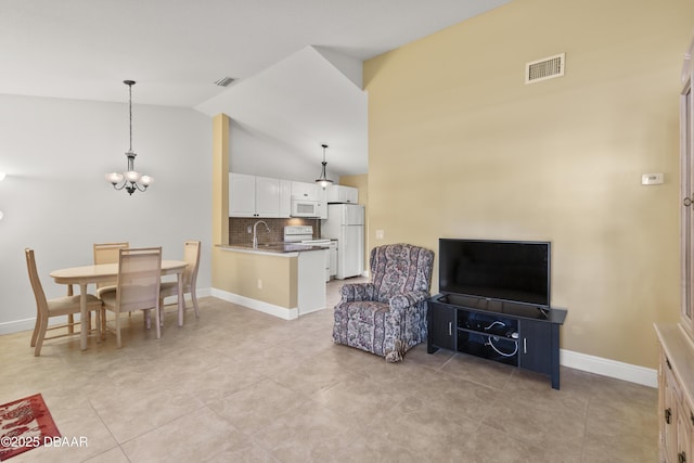 tiled living room with a chandelier, vaulted ceiling, and sink