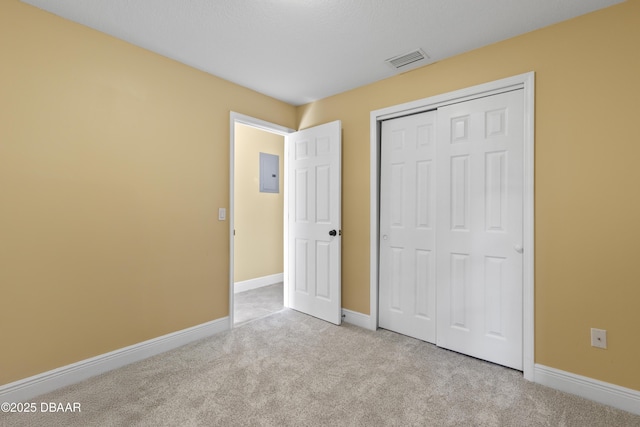 unfurnished bedroom with electric panel, light carpet, and a closet